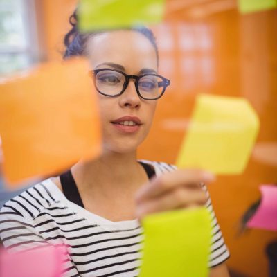 Jeune femme identifiant ses compétences transférables avec des post-it pour les inclure dans sa lettre de motivation